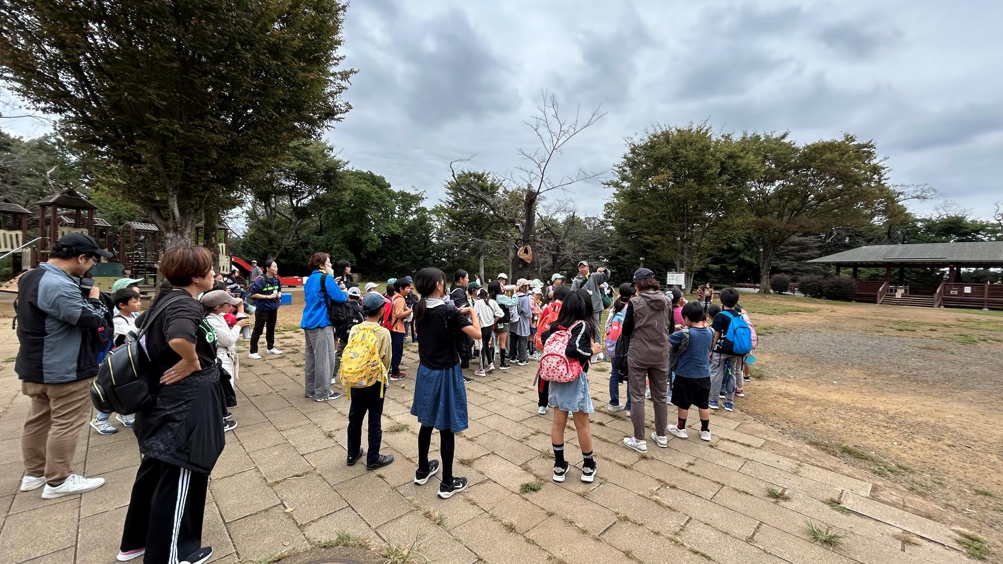 枡形山広場で職員の話を聞く子どもたちの写真