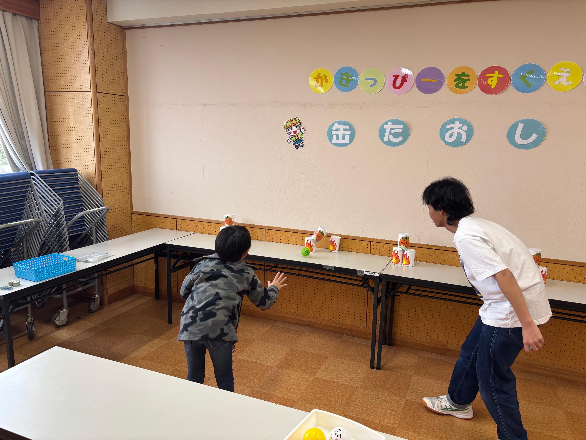 缶たおしをしている子どもの写真