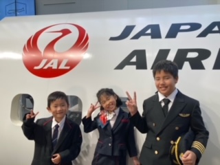 JALスタッフの制服体験をする小学生児童3名の記念写真