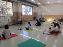 前列に4組、後列に3組の親子が等間隔に間をあけてマットの上に座っている会場全体の写真