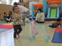 バギーのおもちゃを押して遊んでいる幼い子の写真