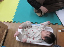 乳児が仰向けになって体重計に乗っている写真