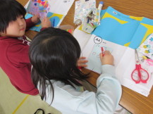 カードを手に持っている子と、カードに文字を書いている女の子の写真