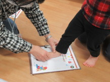 画用紙の上にインクを付けた足をのせている子どもの写真