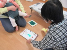 赤ちゃんを膝の上に乗せて足形を取り終わった写真