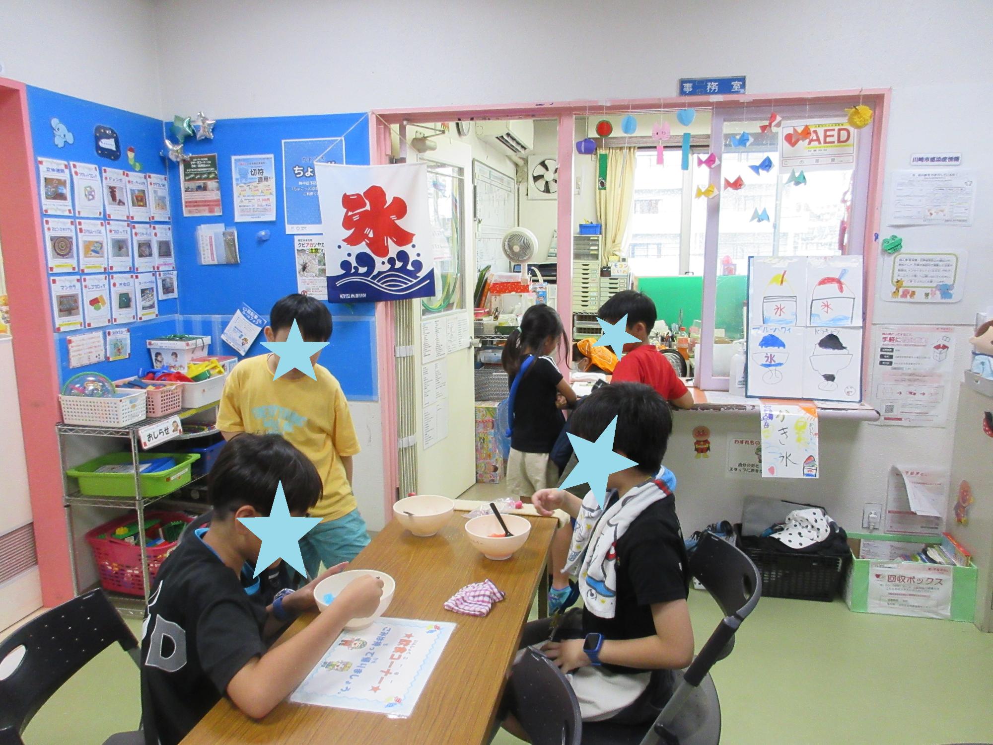 ホールの長机でどんぶりのかき氷を食べる3人の子どもとかき氷の絵のメニューがある受付で注文をする2人の子ども