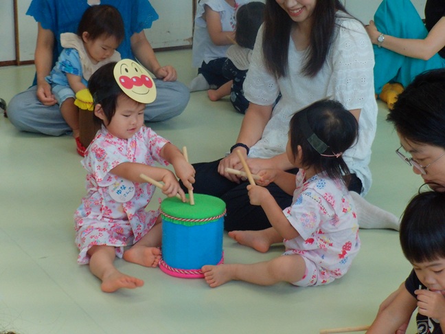 双子の幼児さんが太鼓をたたいている写真