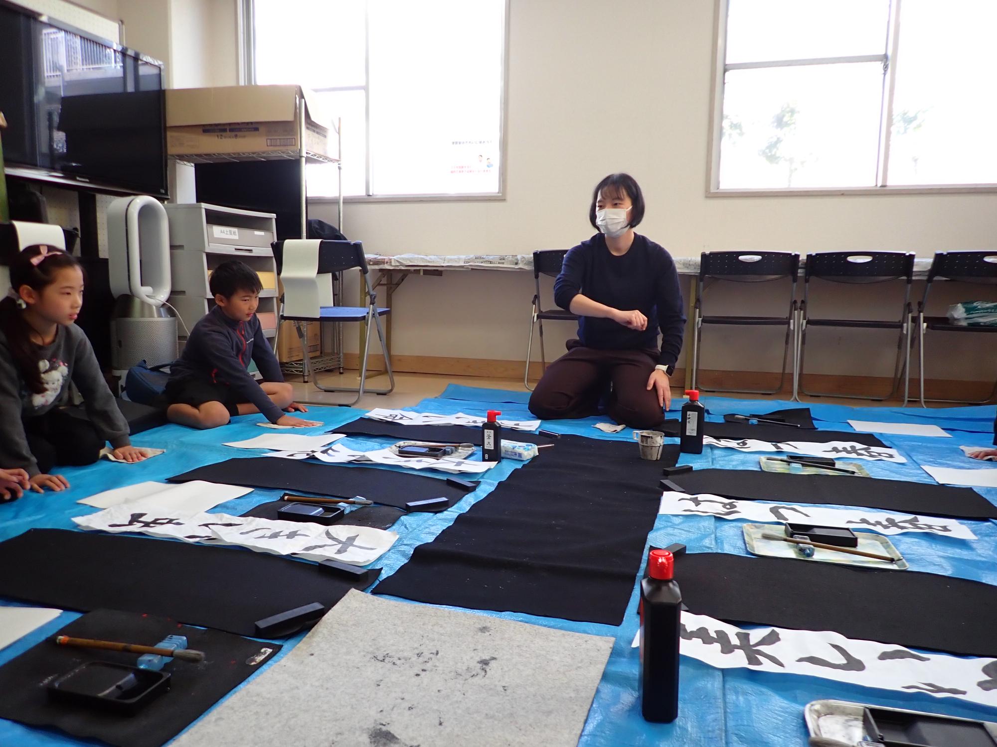 筆の使い方を説明する先生とそれを聞く子ども達の写真