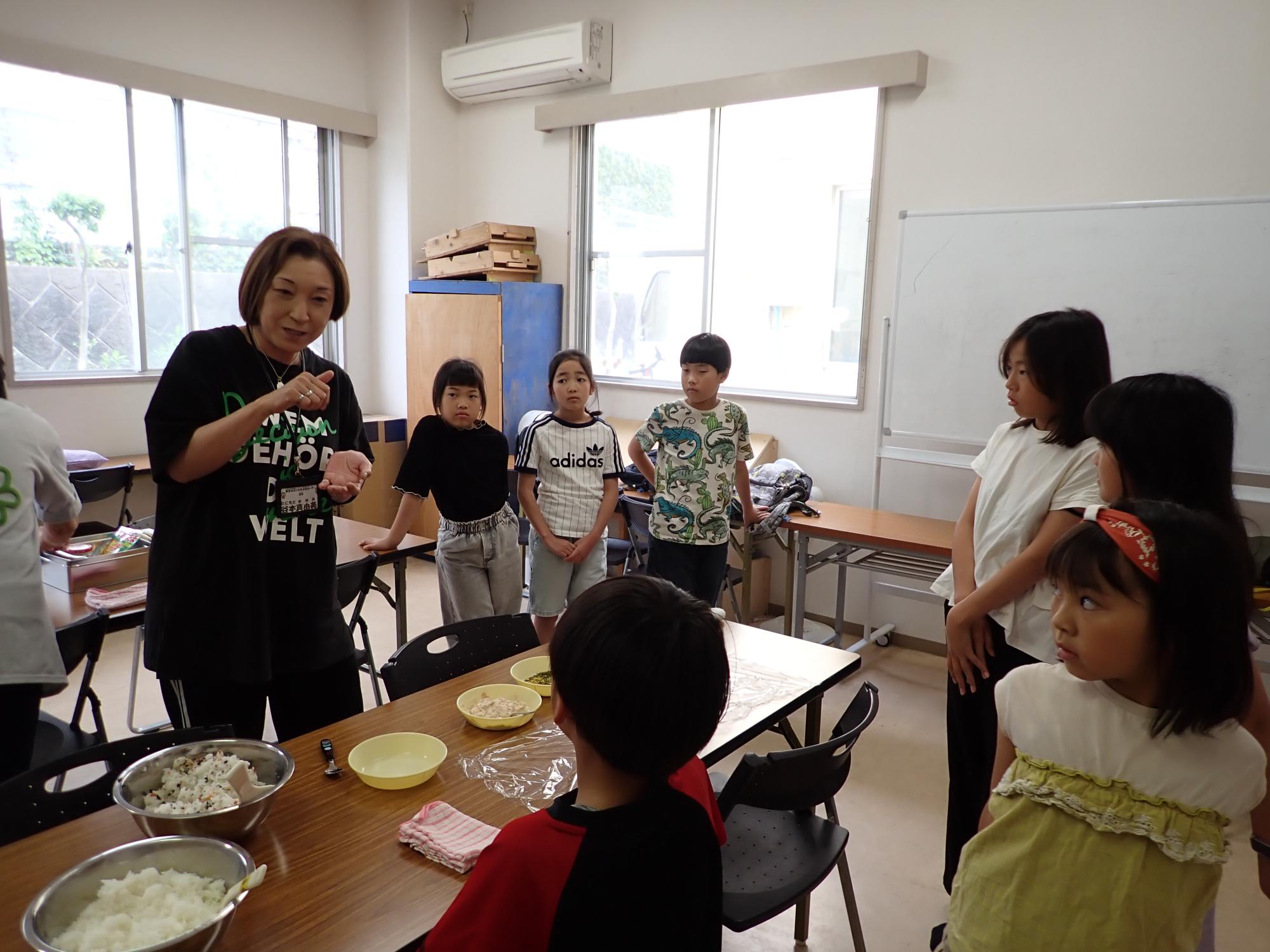 職員からおにぎりの作り方の説明を受ける参加者の写真