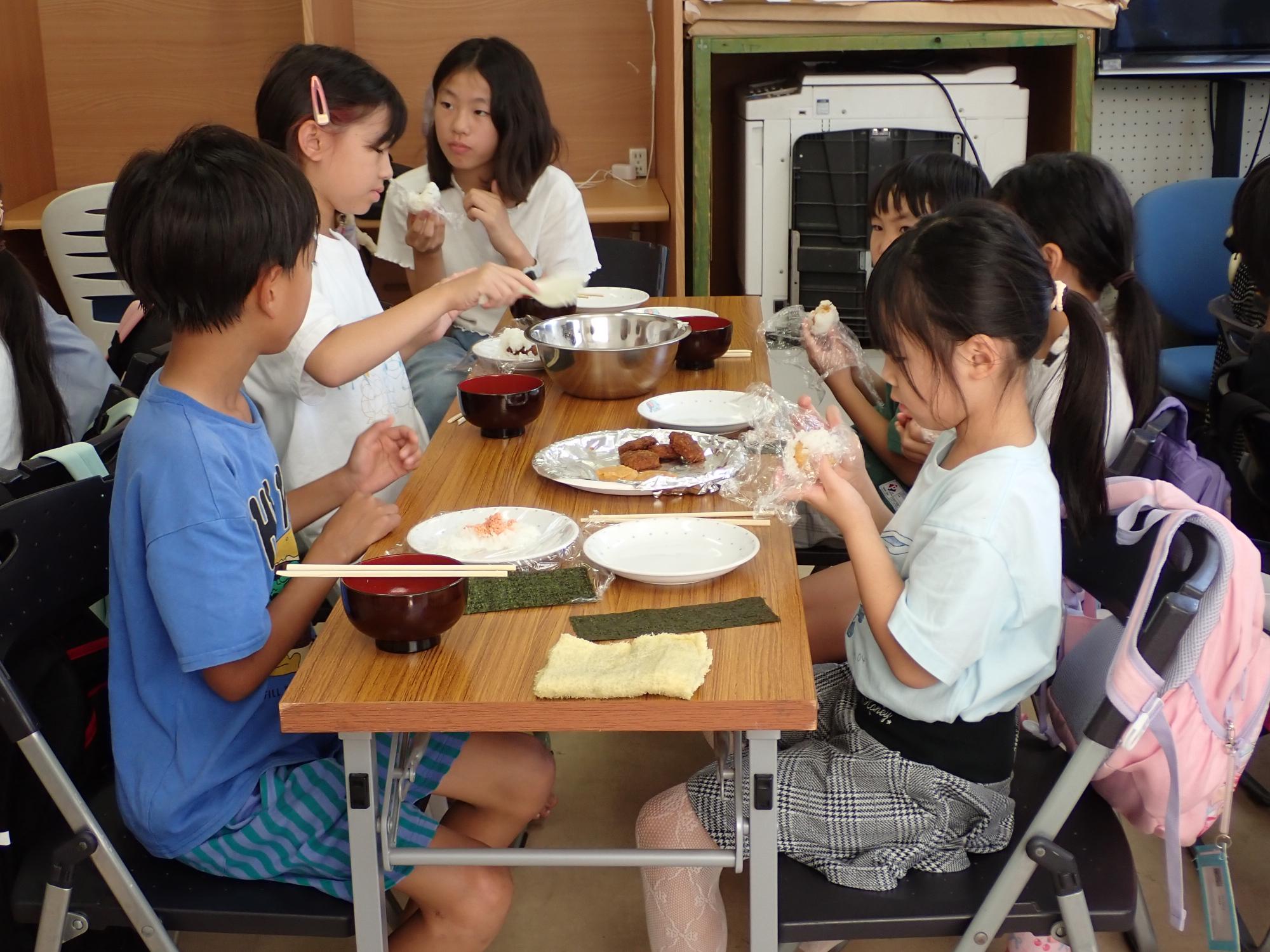 自分の好きな具材でおにぎりを作って食べるこどもたちの写真