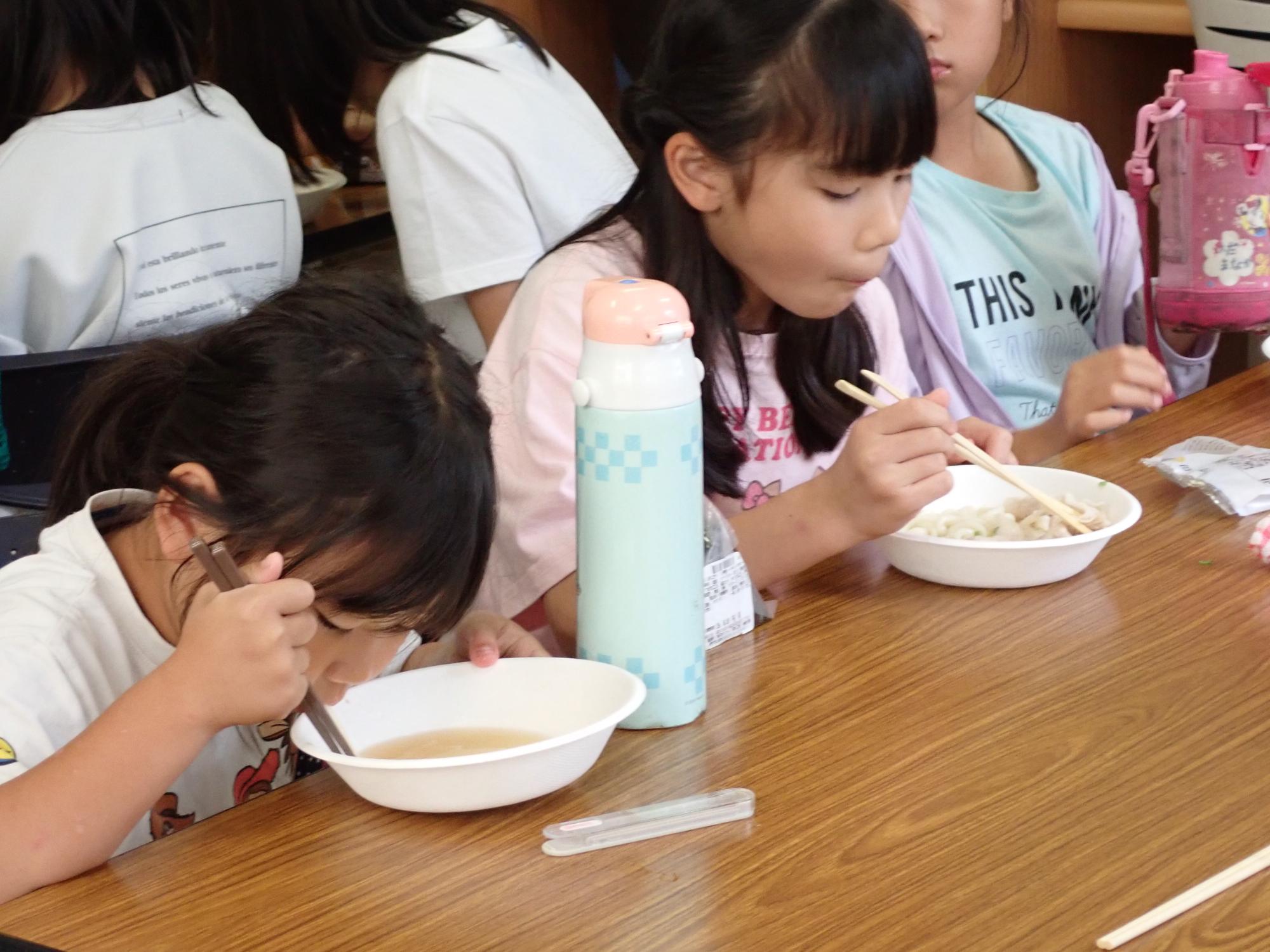 豚しゃぶうどんをほおばるこどもたちの写真