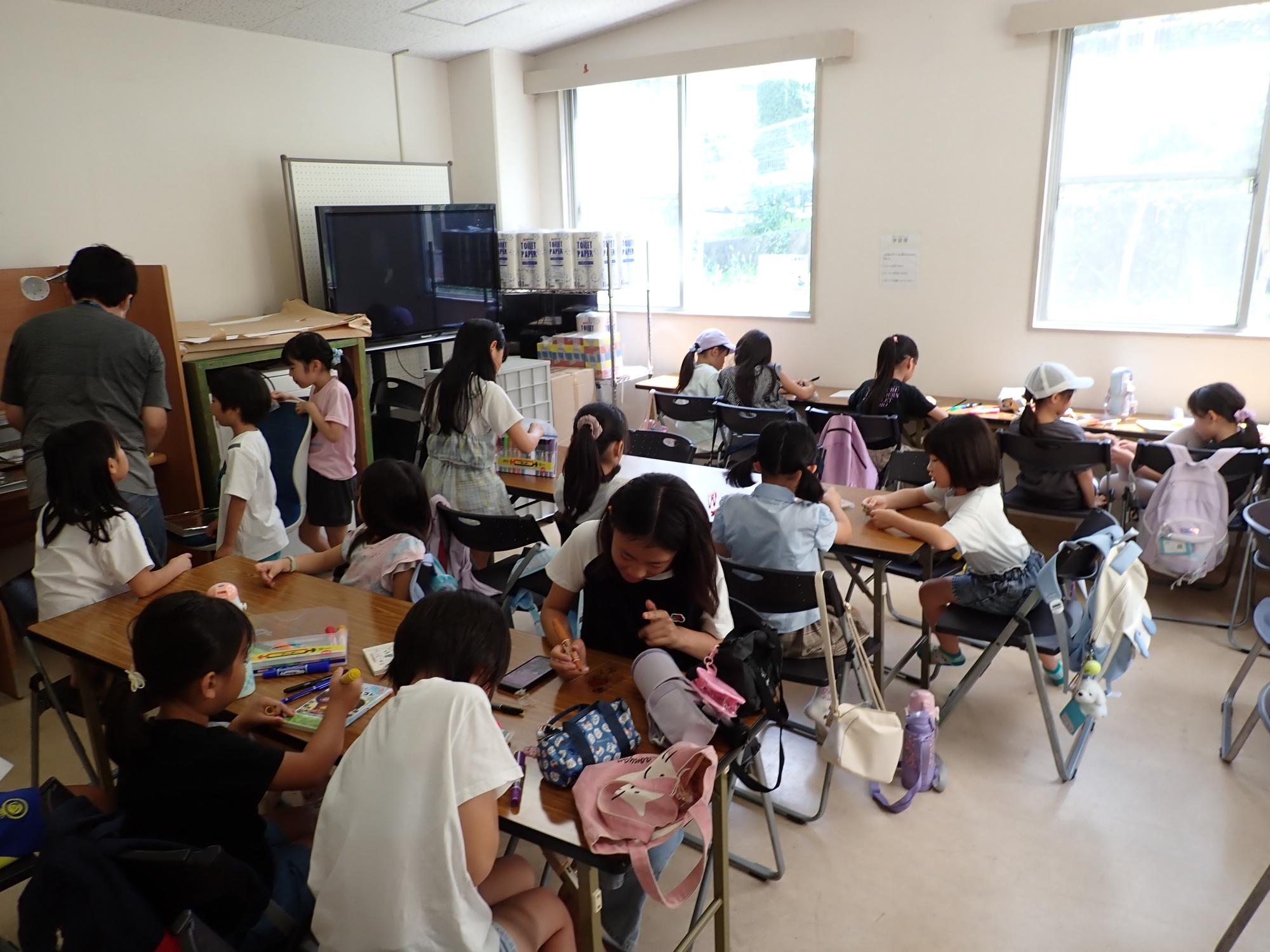 思い思いにプラバンに絵を描くこどもたちの写真
