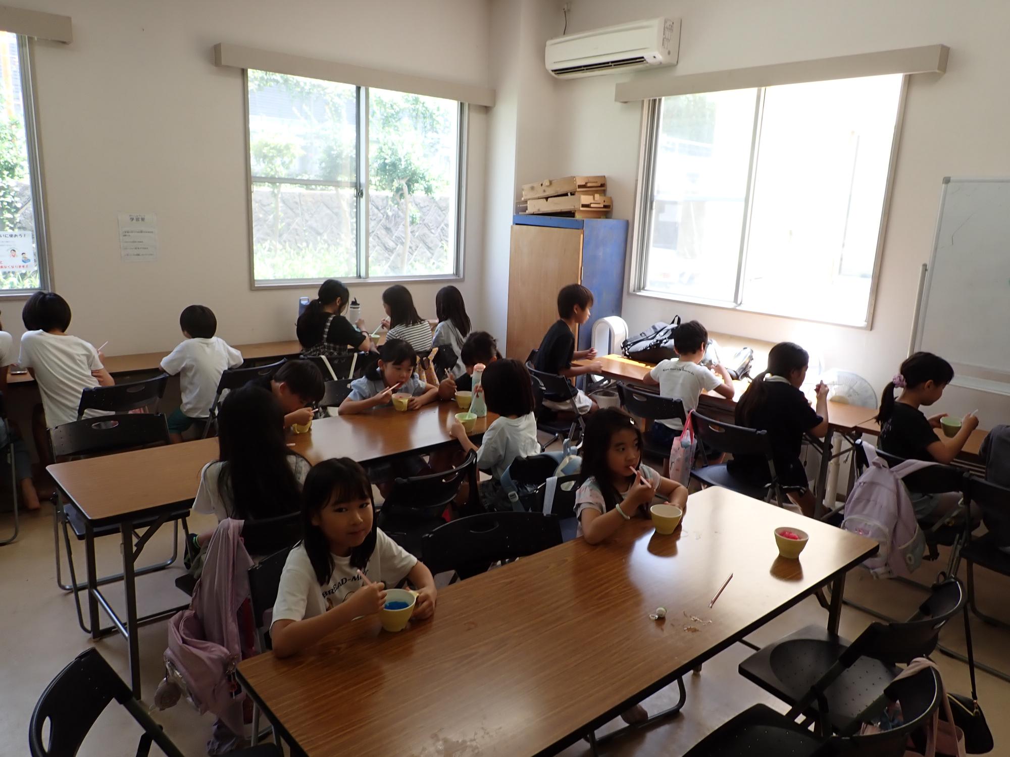好みのシロップでかき氷を食べるこどもたちの写真