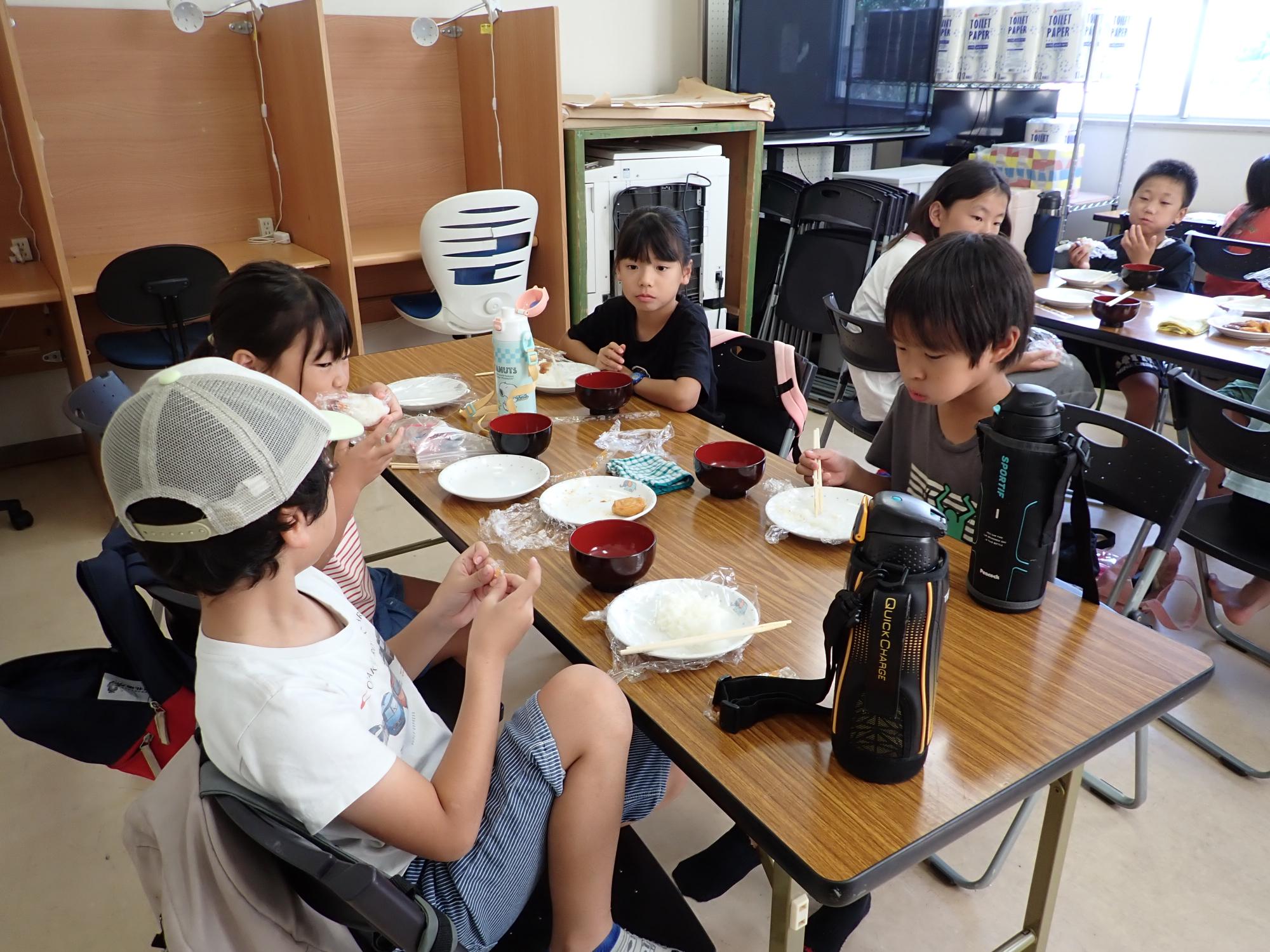 自分の好きな具材でおにぎりを作って食べるこどもたちの写真