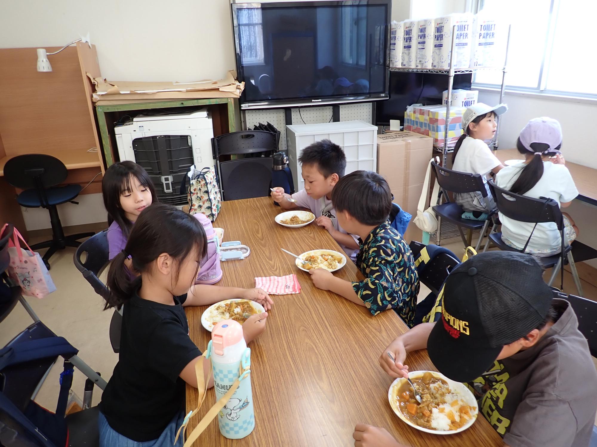 カレーをほおばるこどもたちの写真