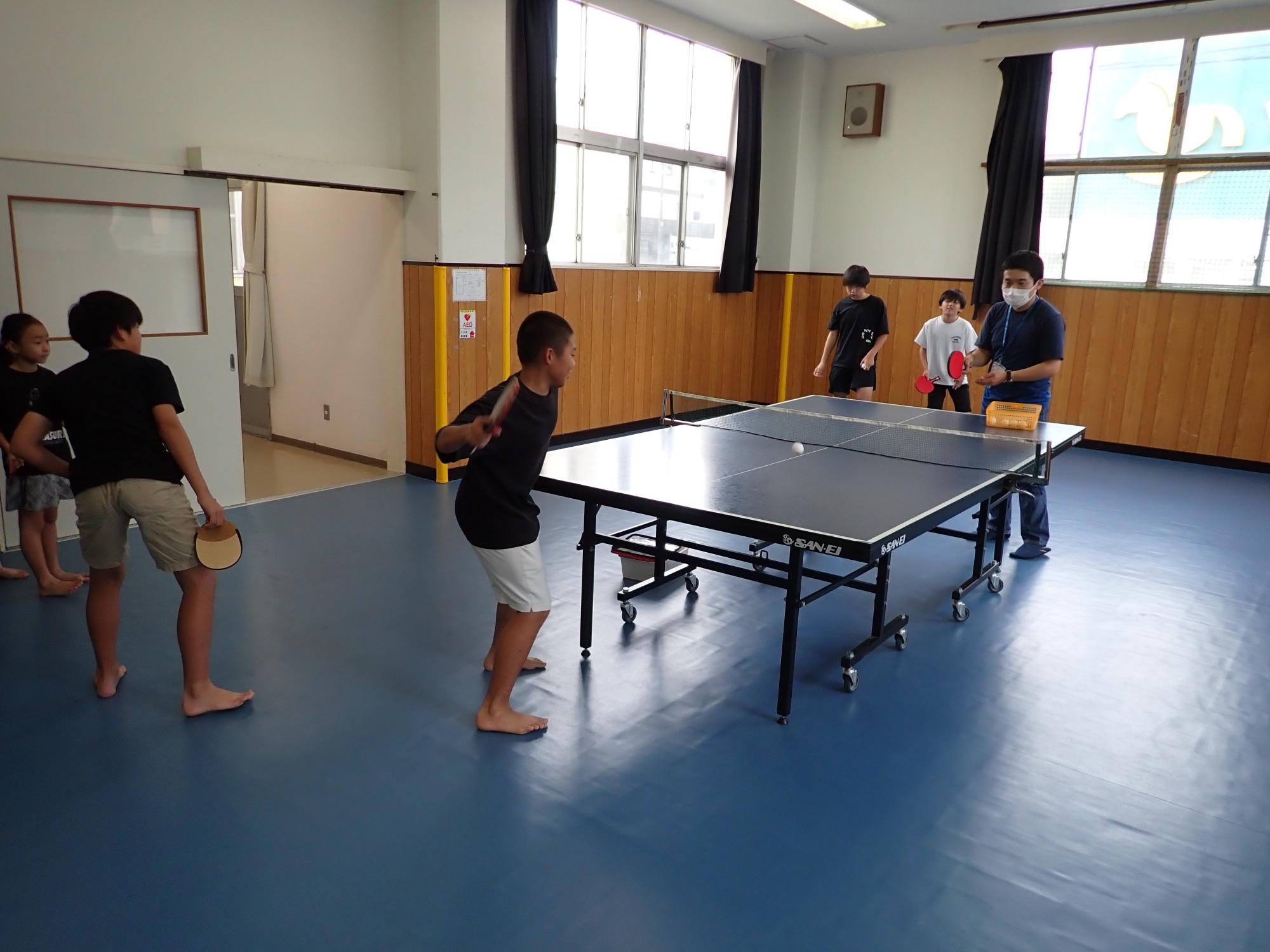 職員のサーブを打ち返そうとする参加者の写真