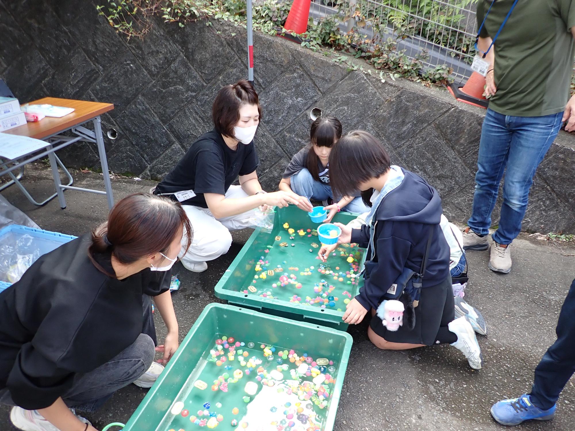 スーパーボールすくいをする子どもとお手伝いの方の写真