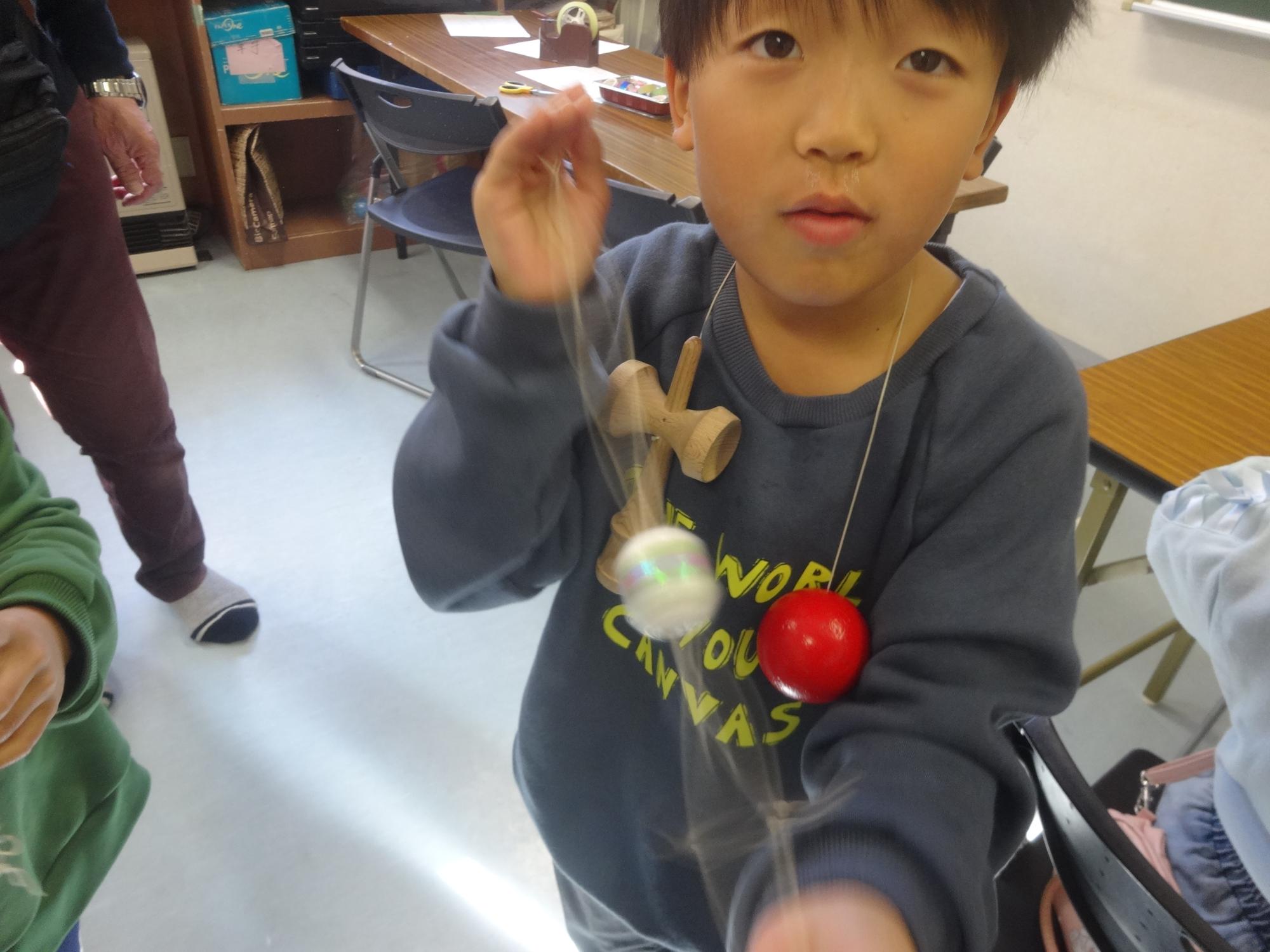 完成したブンブンごまを回す小学生男子の写真