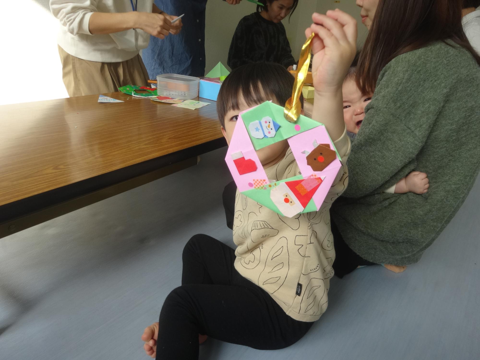 完成したクリスマスリースを見せる幼児