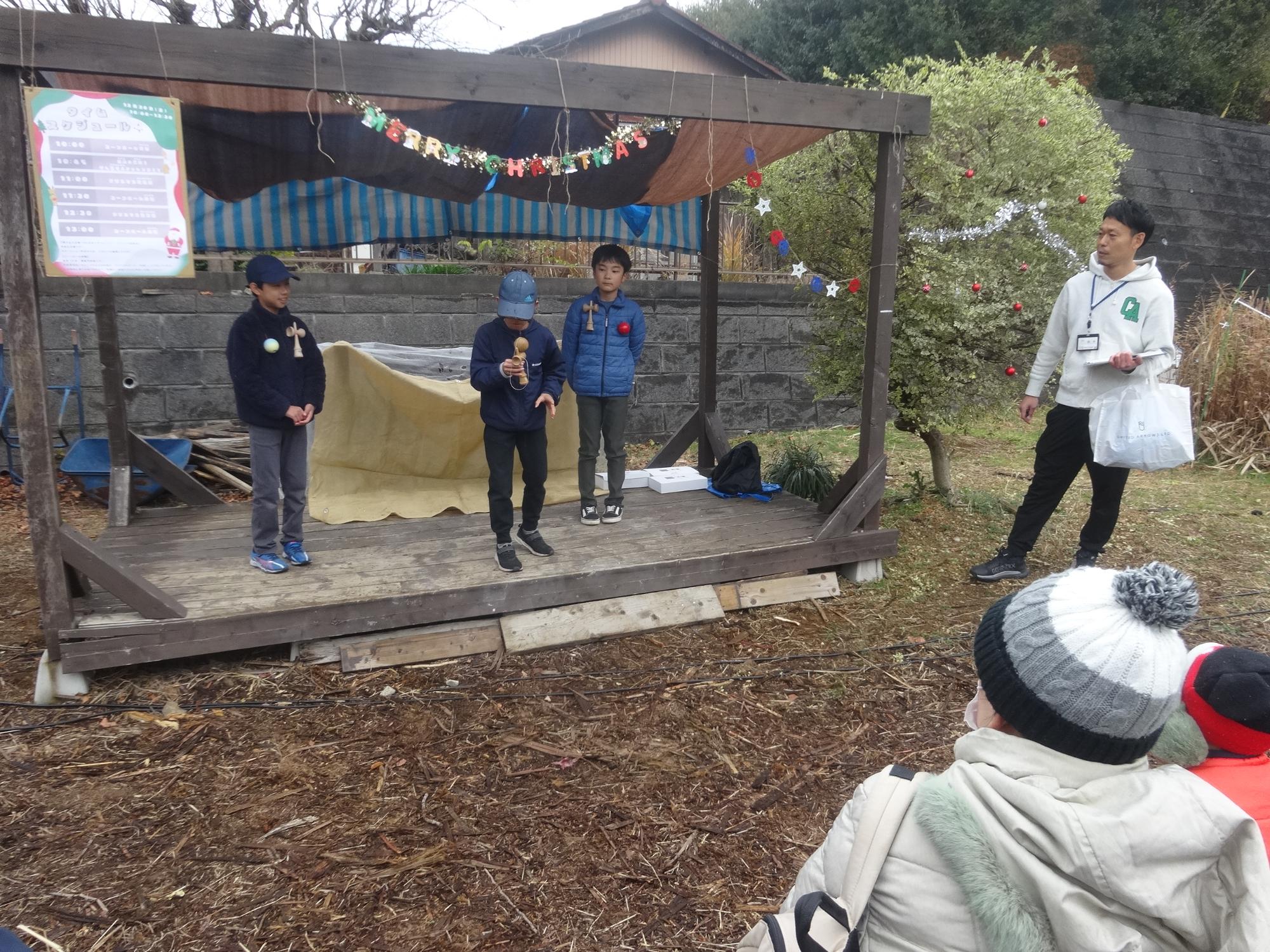 野外ステージでけん玉の技を披露する小学生
