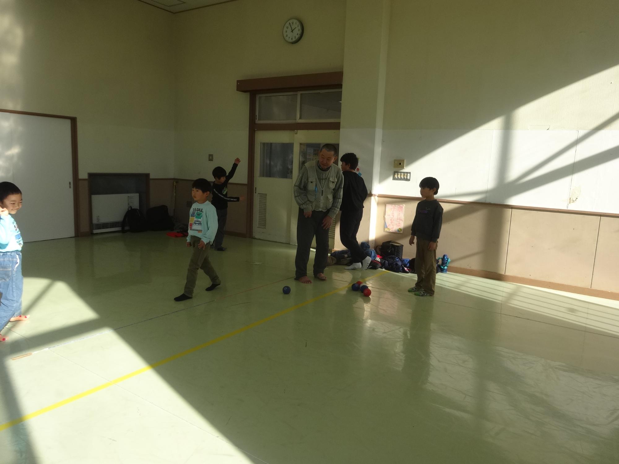 小学生と幼児親子が一緒にボッチャを楽しんでいる写真