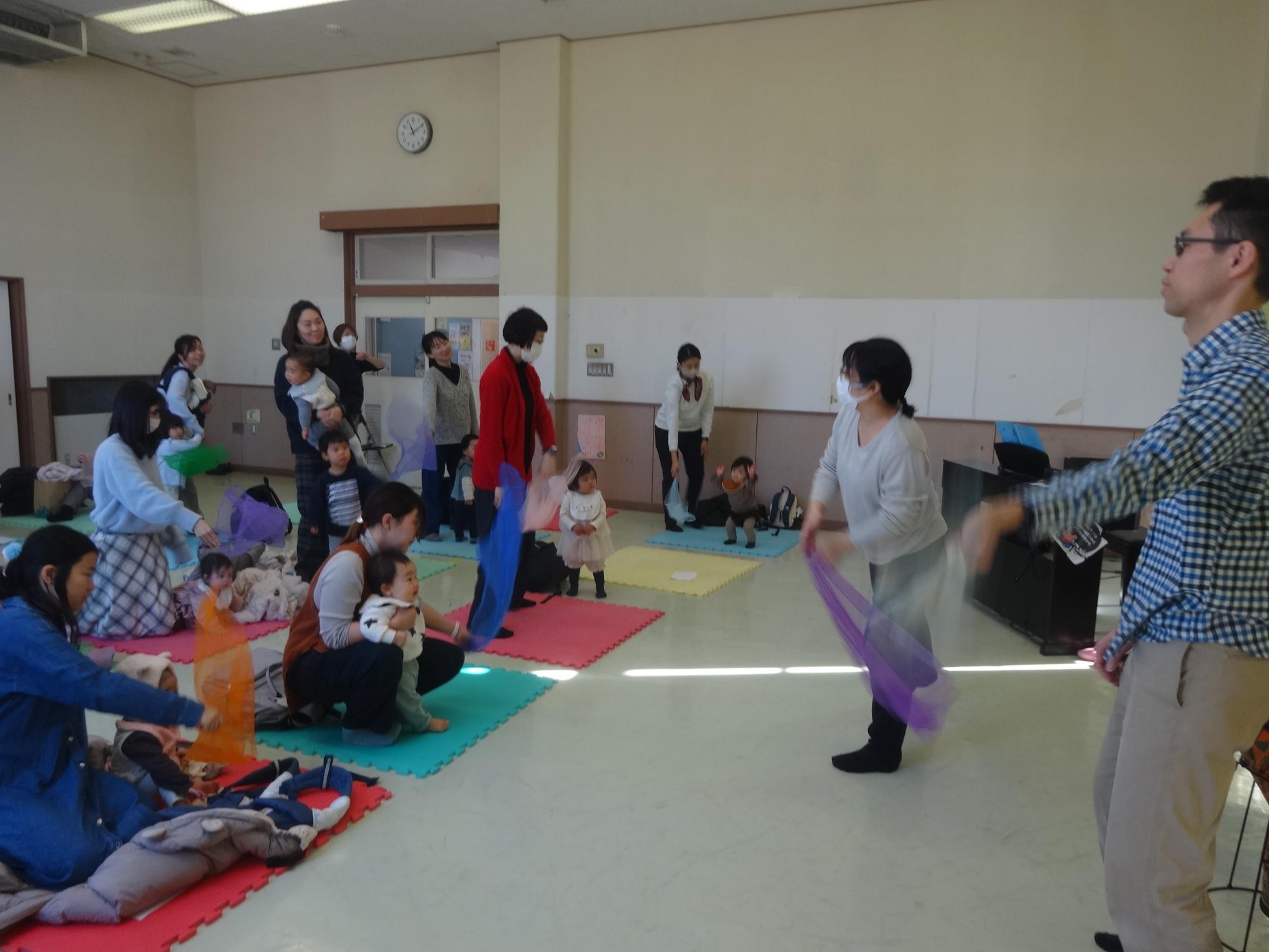 スカーフあそびをする乳幼児親子の写真