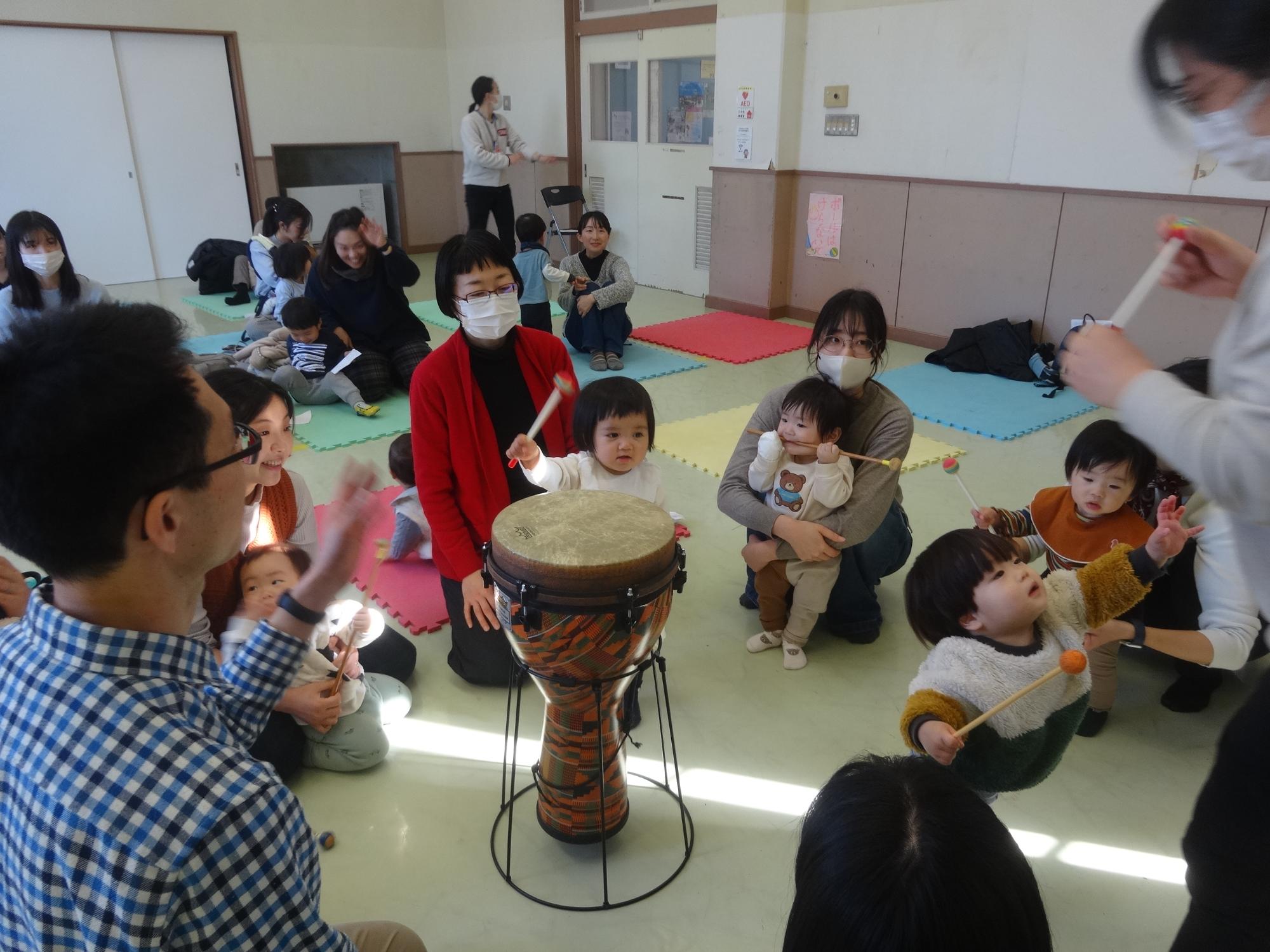 お餅つきのマネっこあそびて太鼓をたたく幼児たちの写真