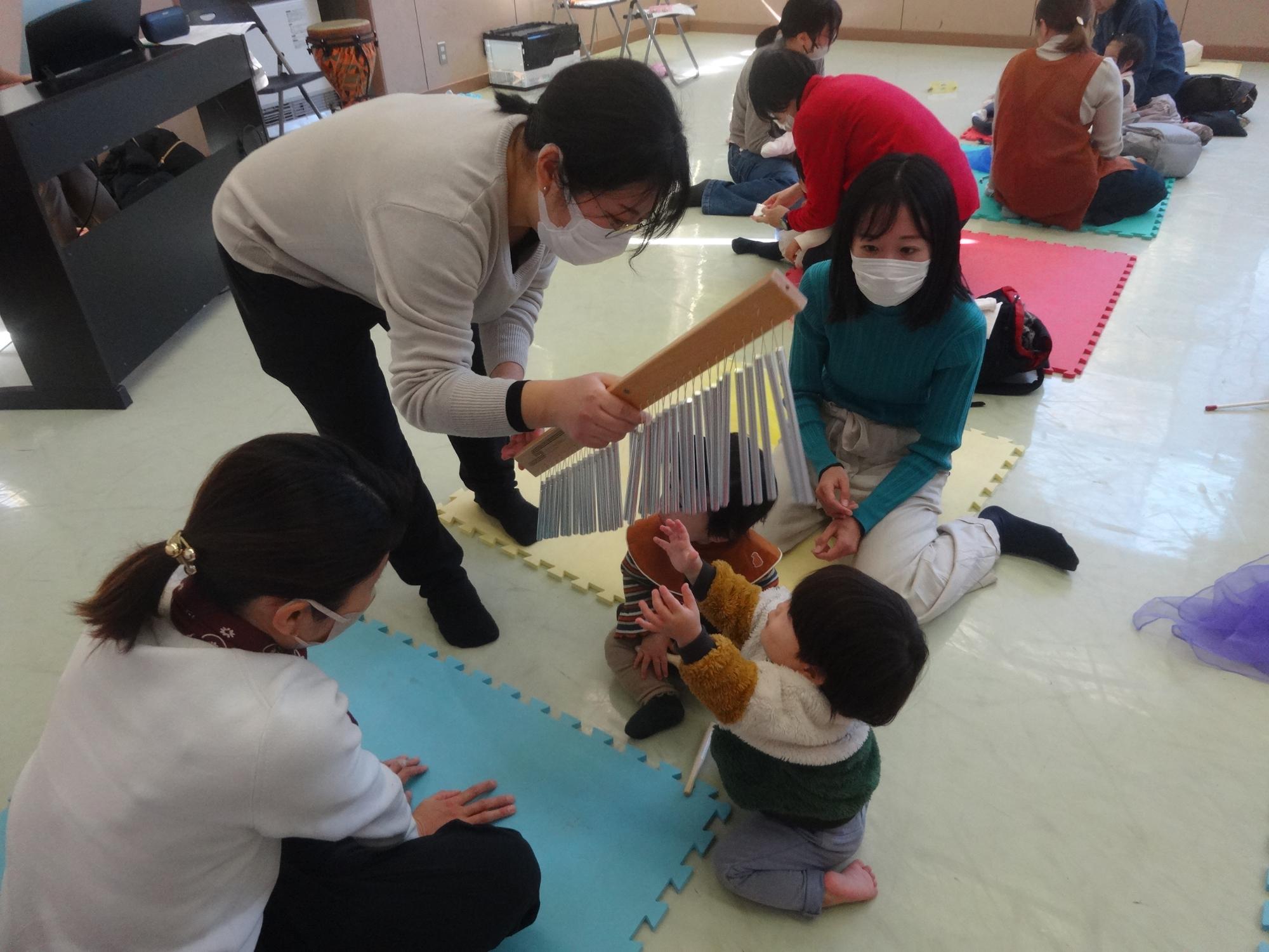 音楽にあわせてウインドチャイムに触れる幼児