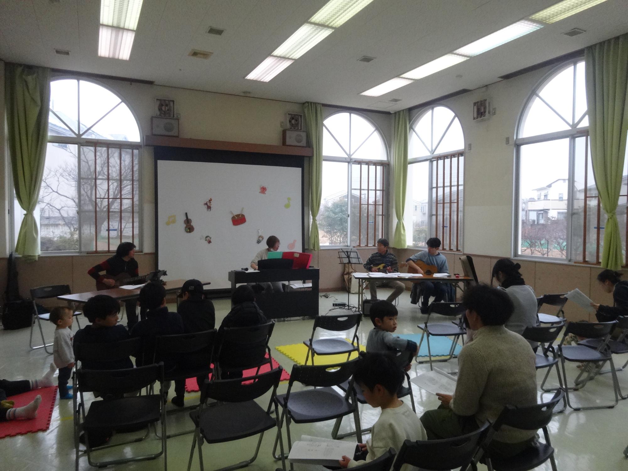 ギター3人とピアノの伴奏でみんなで歌を歌っている写真