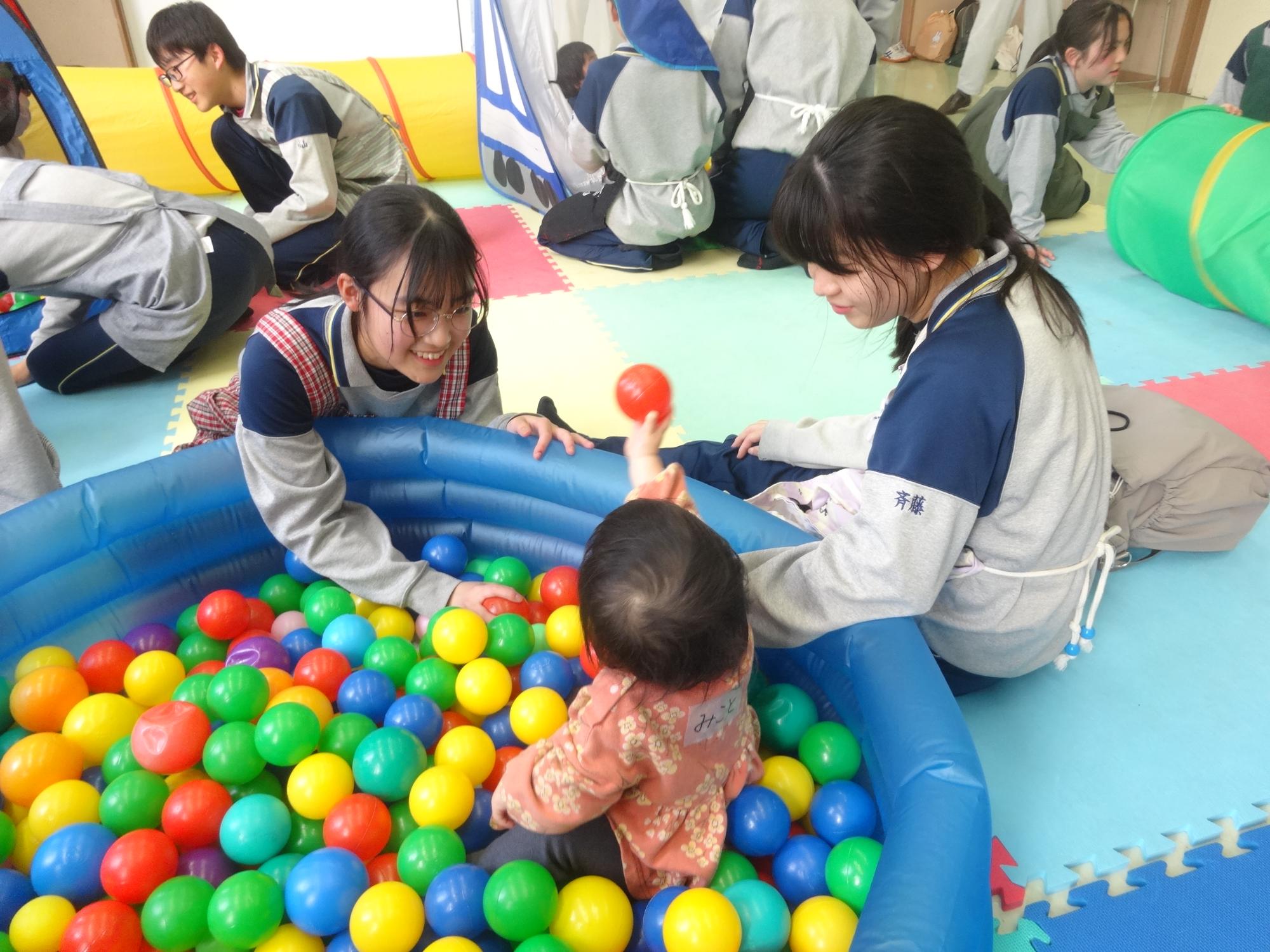 ボールプールで遊ぶ幼児と中学生の写真