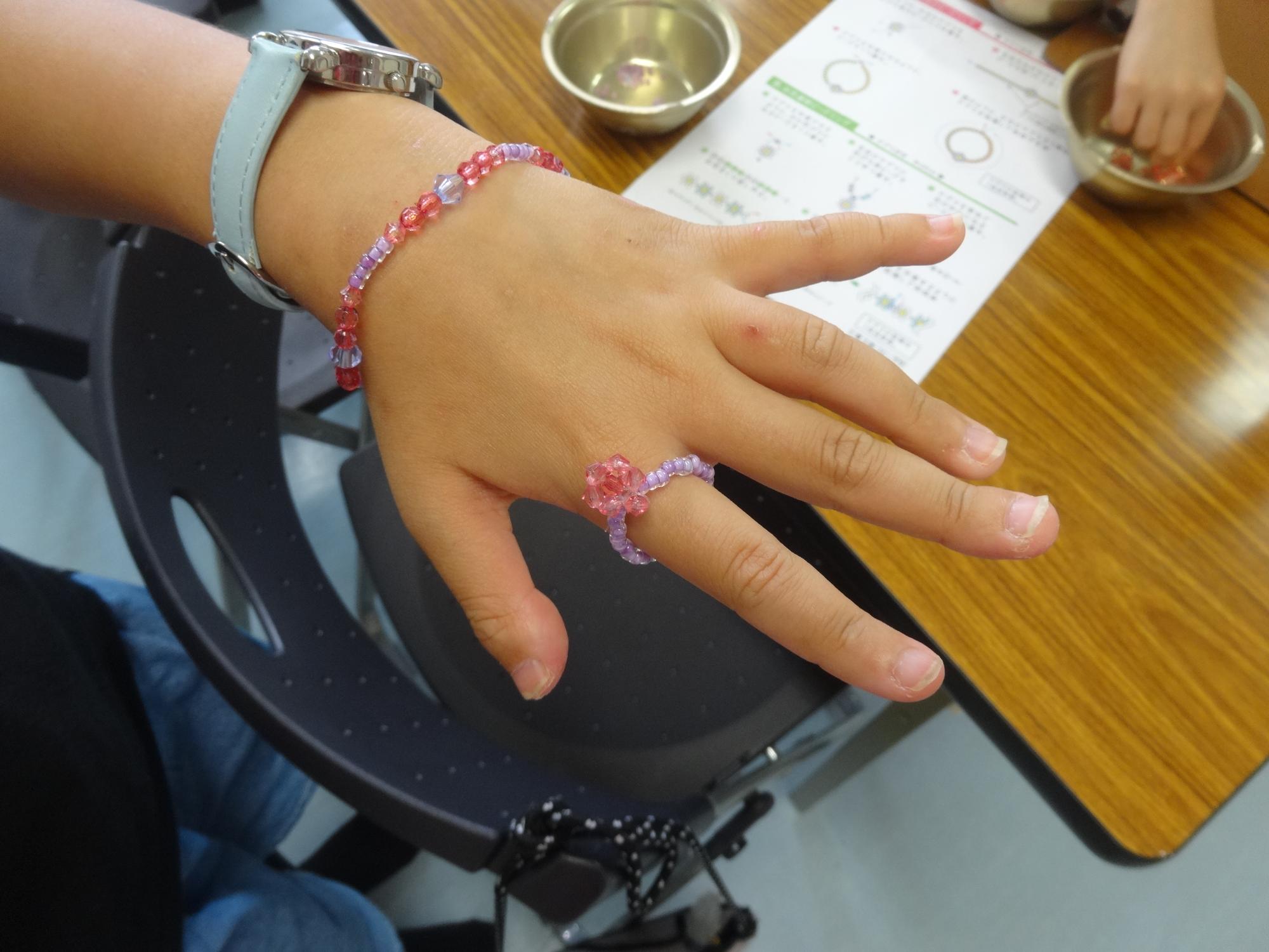 自分で作った指輪とブレスレッドを付けている小学生の手元