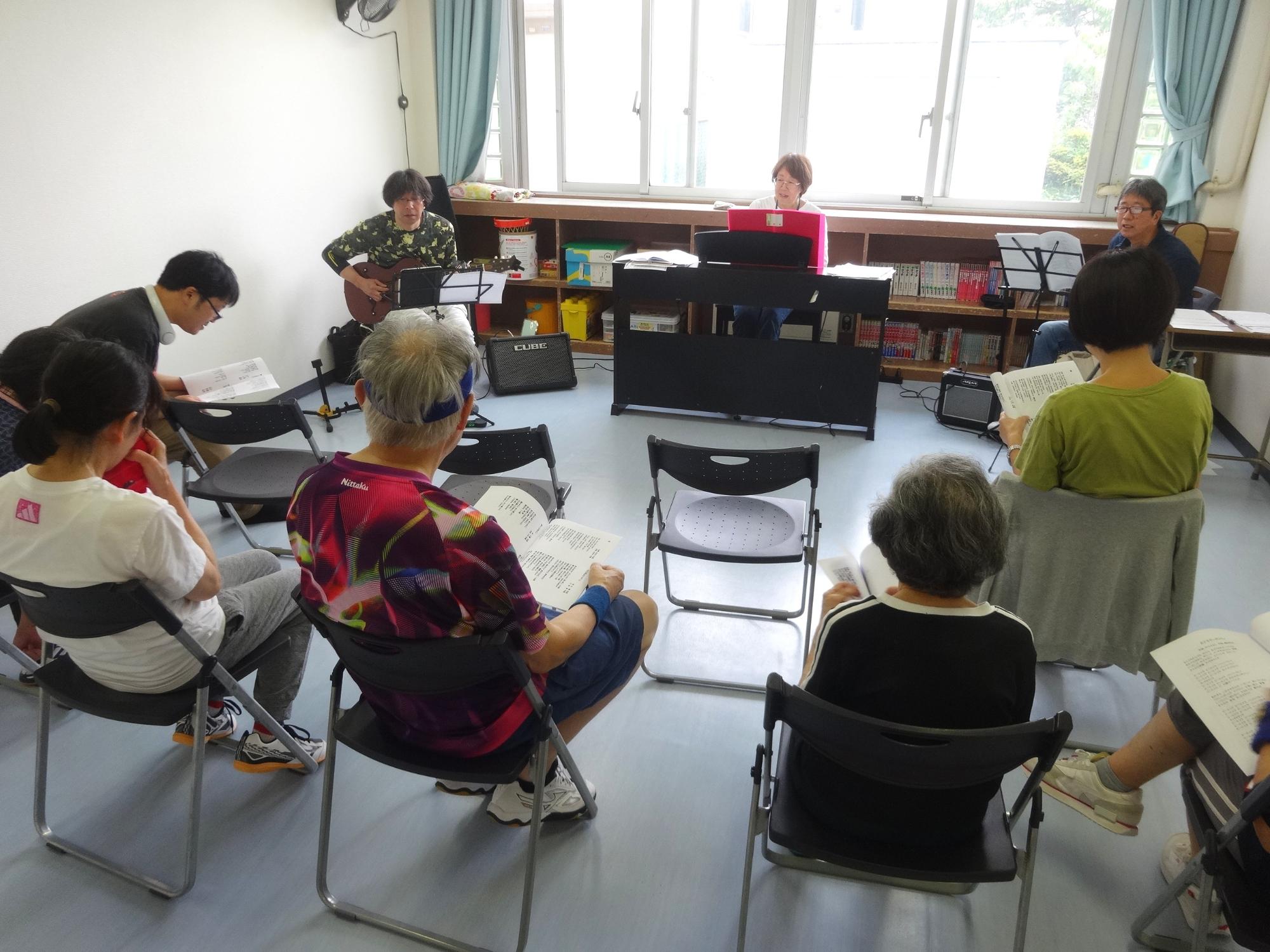 ピアノ、ギターの演奏を聞きながら、歌集を見ながら声を合わせて歌う近隣のみなさんの写真