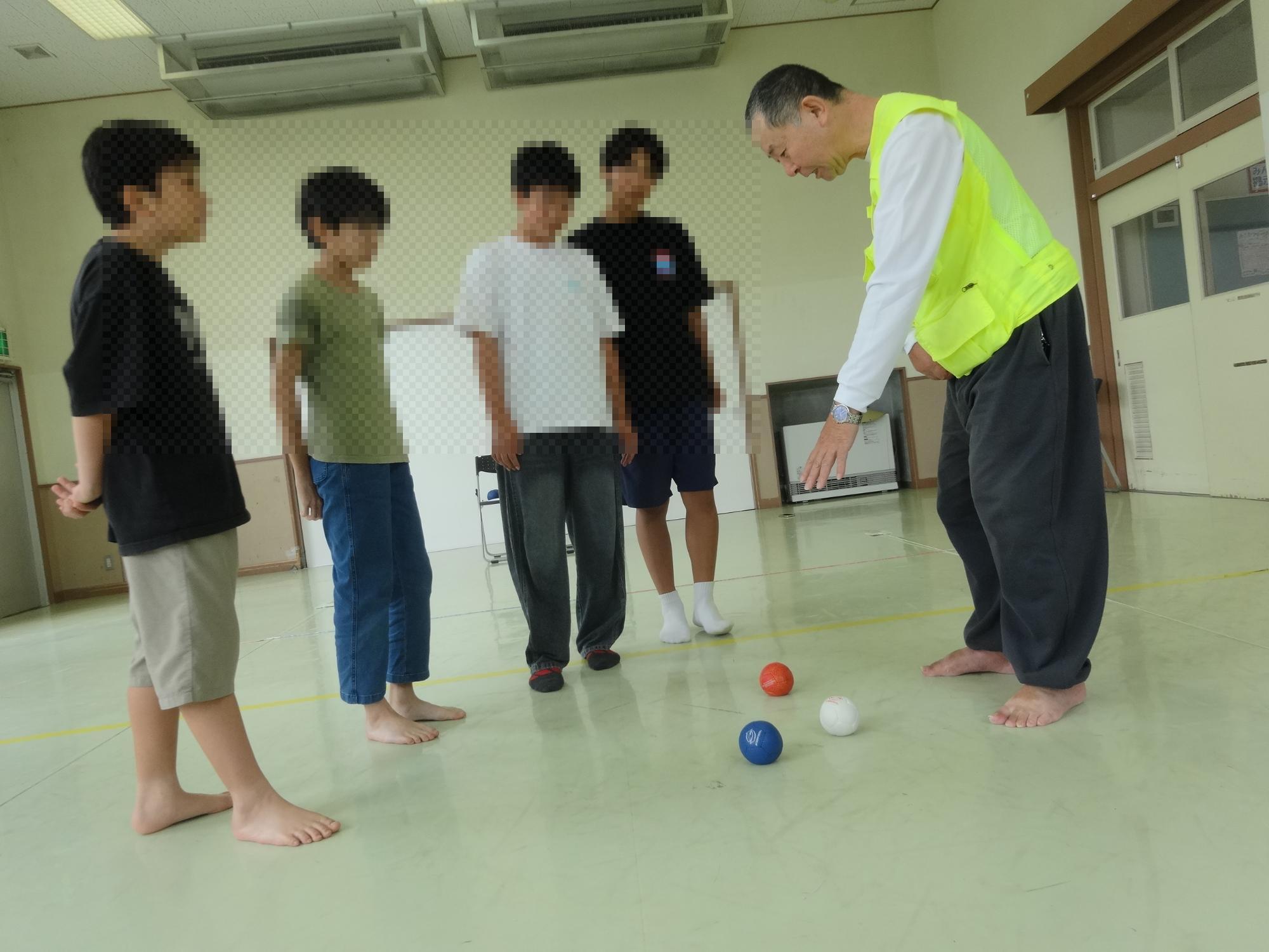 先生からボッチャのルール説明を受ける4人の中学生