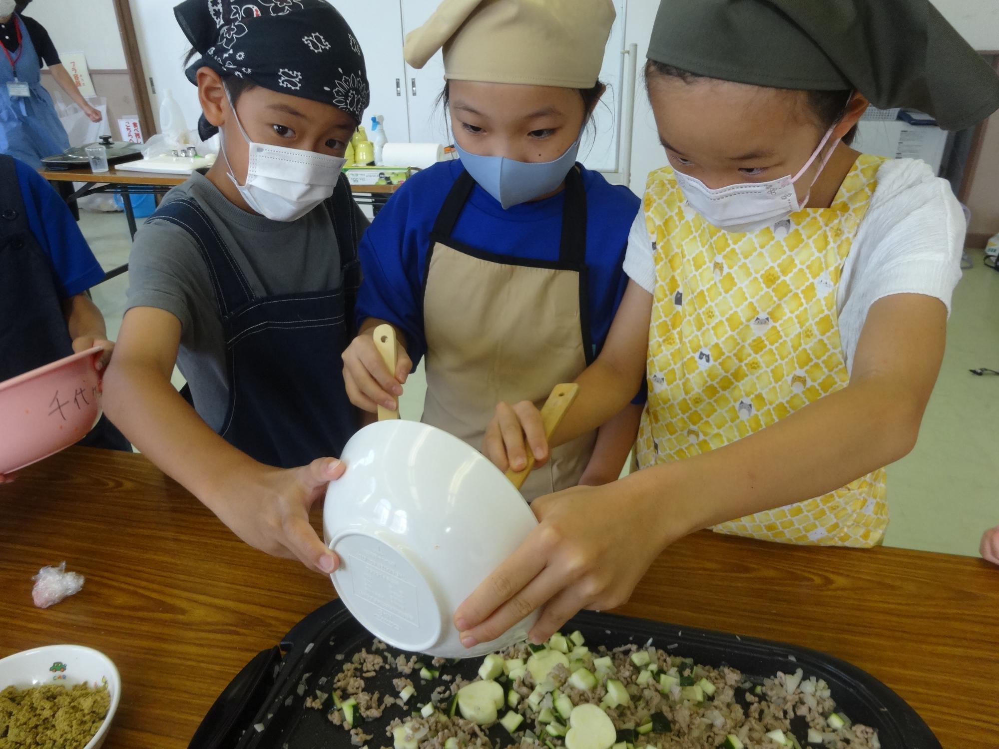 野菜を炒める小学生3人