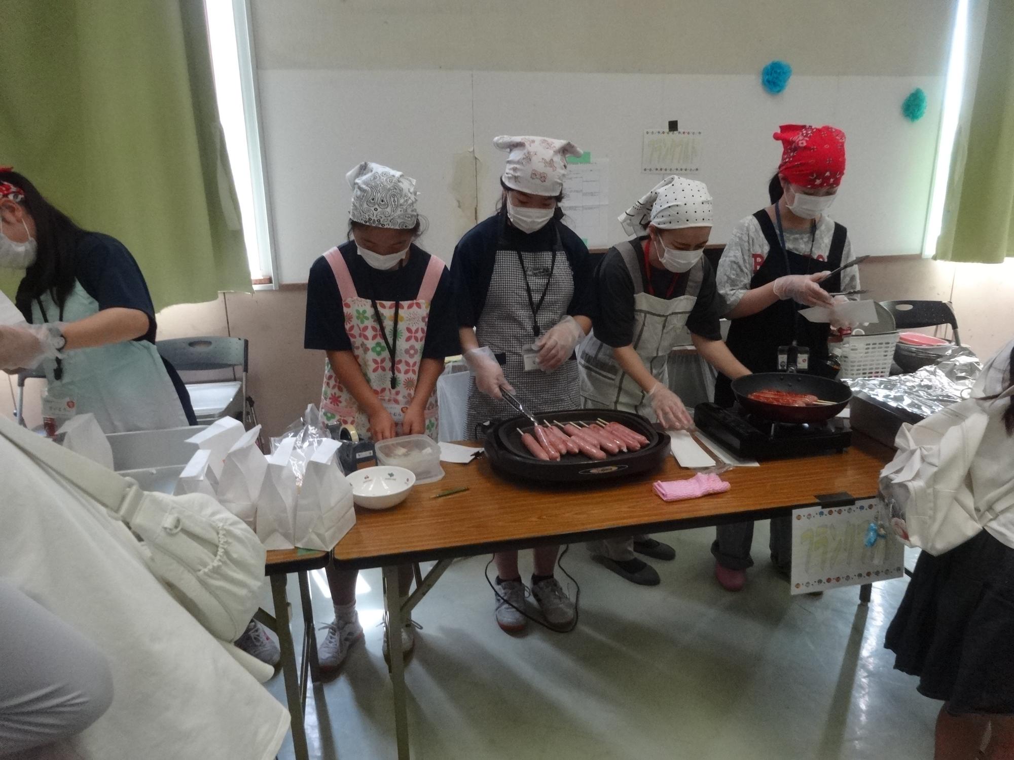 フランクフルトを調理するボランティアの中学生