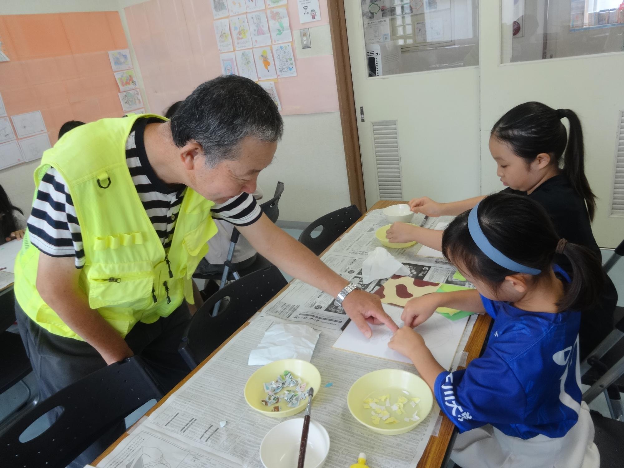 ちぎり絵のやり方を先生に教えてもらう小学生
