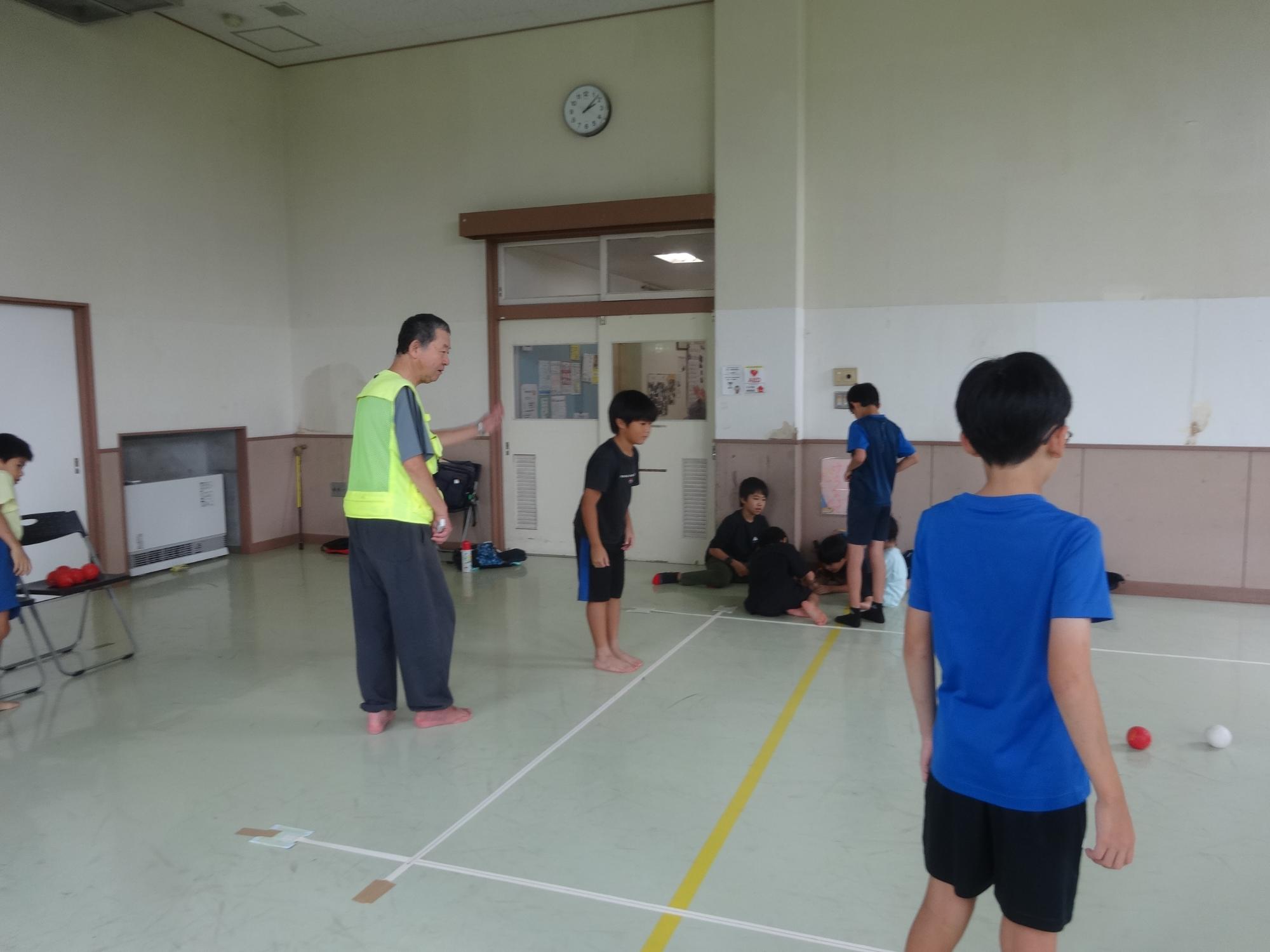 ボッチャで青いボールを投げようと、ねらいを定めている小学生の写真