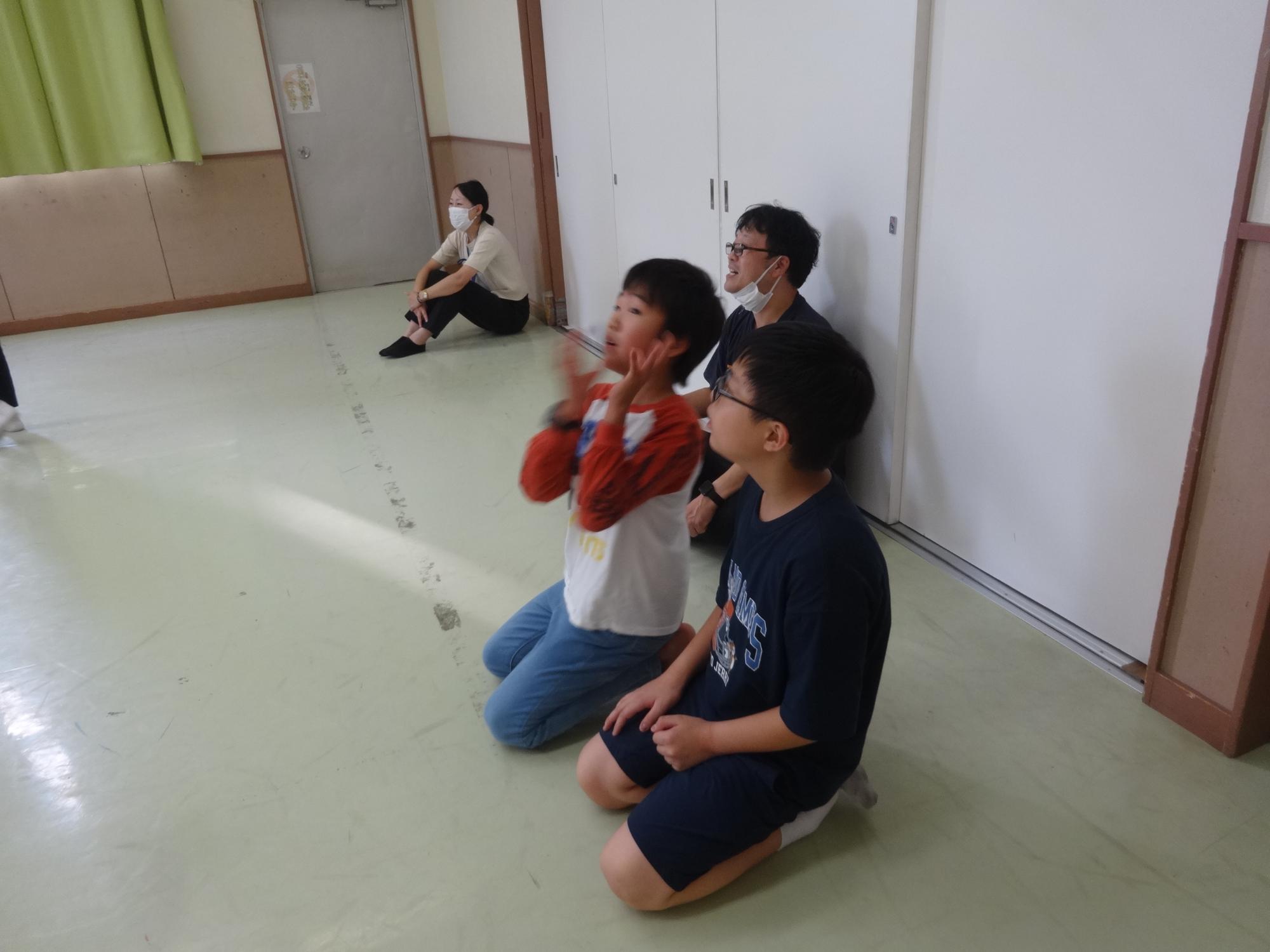 キャップを落としてしまったので座って応援をする小学生の写真