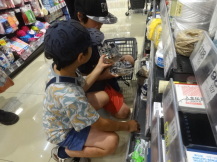 2人の男の子が会議で使う備品をお店の棚から選んでいる写真