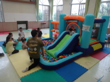 カラフルなボールが沢山あるバルーン遊具で遊ぶ親子たちの写真