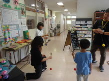 施設内の通路でけん玉の練習をしている子供たちの写真