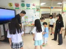 けん玉検定を受ける子供たちと出来ているか判定する検定員の男性の写真