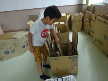 大量に置かれた段ボールからどれにしようか選ぶ男の子の写真
