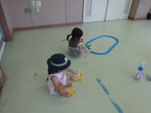 部屋のすみでおもちゃで遊ぶ小さい子どもたちの写真
