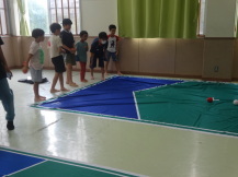 広い部屋の中でボッチャをする子どもたちの写真