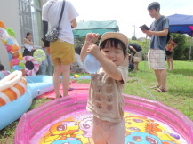 薄い水色の水風船をつかんで遊ぶ笑顔の子どもの写真