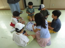 ベイブレードスタジアムの台の周りを円状になって座った6名の子どもたちが話をしている様子の写真