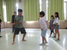 じゃれ合いながら対面で立っている2名の子どもを回りの参加者が見つめている写真
