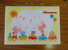 かわいいイラストが書かれた色紙の真ん中に赤いインクで子どもの手形が押されている写真