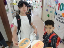 カメラに向かってお皿に乗せた「らくがきせんべい」を見せながら記念撮影を行っている来場者2名の写真